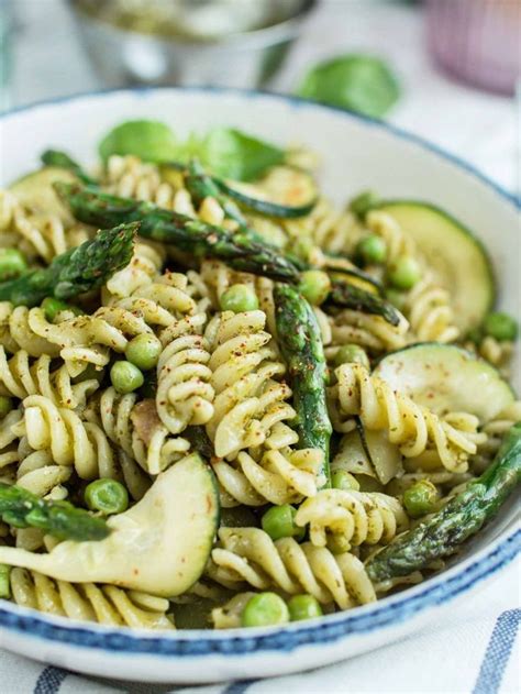 a bowl filled with pasta and asparagus on top of a blue and white table cloth