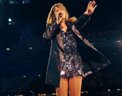 a woman standing on top of a stage with her hands in the air and singing