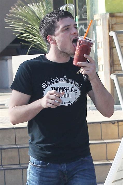 a man holding a drink up to his mouth while standing next to stairs and ...