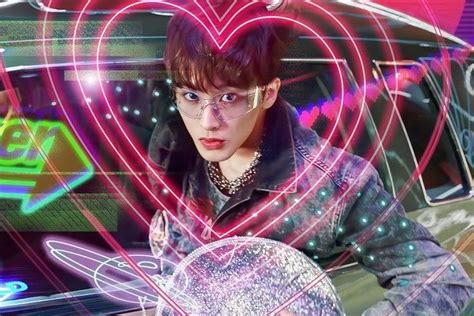 a young man holding a heart shaped object in front of a car with neon lights