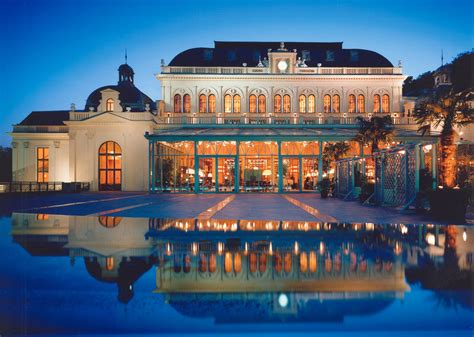 a large building with many windows next to a body of water at night in ...