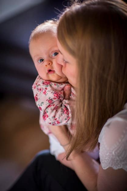 Premium Photo | Woman kissing a young baby on cheek