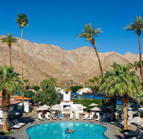 an outdoor swimming pool with palm trees and mountains in the backgroung area