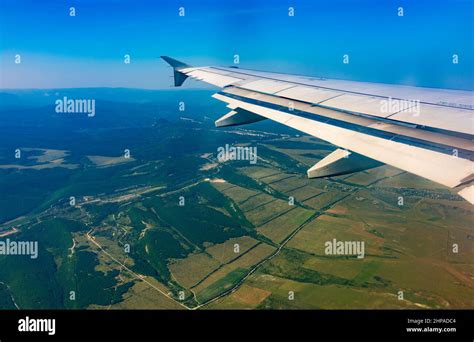 View of airplane wing, blue skies and green land during landing ...