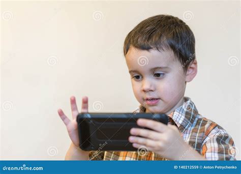 Portrait of a Smiling Little Boy Holding Mobile Phone Over Light ...