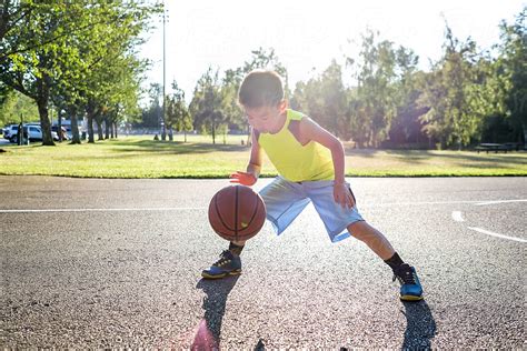 Asian Kid Dribbling A Basketball In An Outdoor Basketball Court | Stocksy United