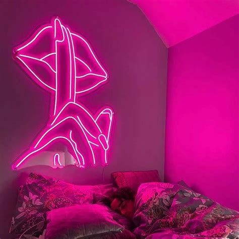a bedroom with pink walls and a neon sign above the bed