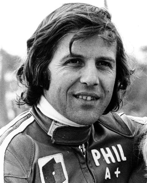 a black and white photo of a man in a racing suit smiling at the camera