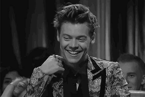 a man smiling while sitting at a table in front of another man with his hand on his tie