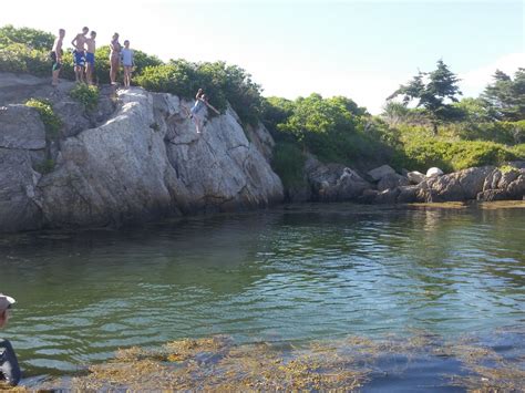 some people are standing on the rocks by the water