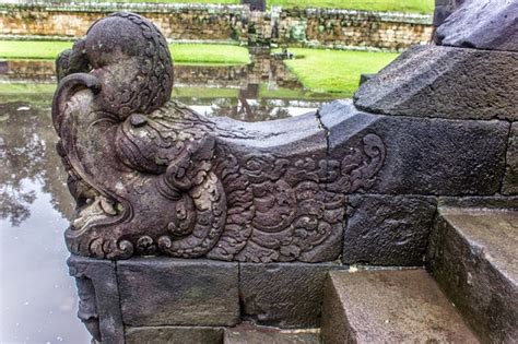 a stone statue sitting on top of steps next to a body of water in the ...