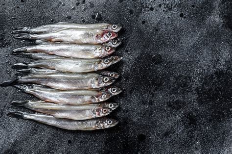 Premium Photo | Raw fresh capelin fish on black table