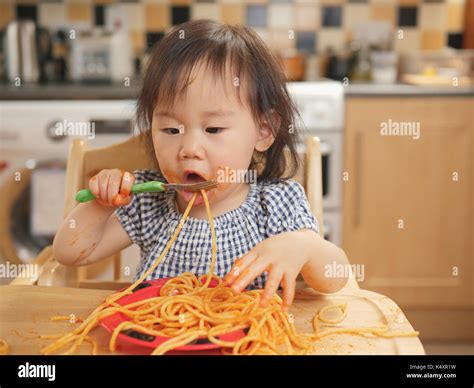 baby girl eating messy spaghetti at home Stock Photo - Alamy