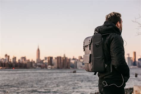Man Wearing Black Bubble Jacket and Black Leather Backpack Near Bay · Free Stock Photo