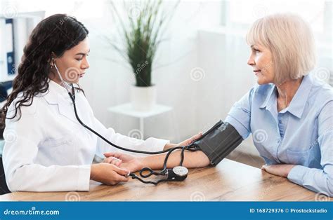 Female Nurse Checking Blood Pressure of Mature Woman Stock Photo ...