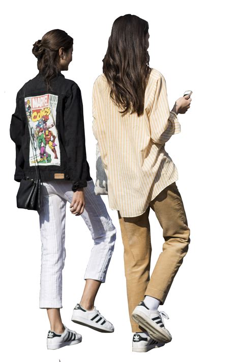 two women standing next to each other while looking at their cell phones in the same direction