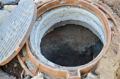 open sewer on the street. metal tunnel for water drainage, creating a ...