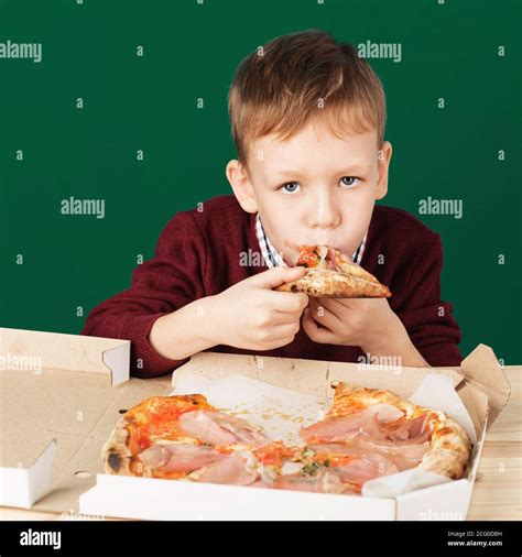 Children eat Italian pizza in the cafe. School boy is eating pizza for lunch. Child unhealthy ...