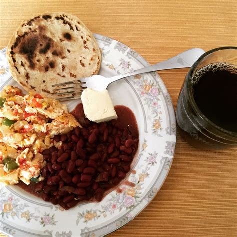 a white plate topped with beans and rice next to a fork