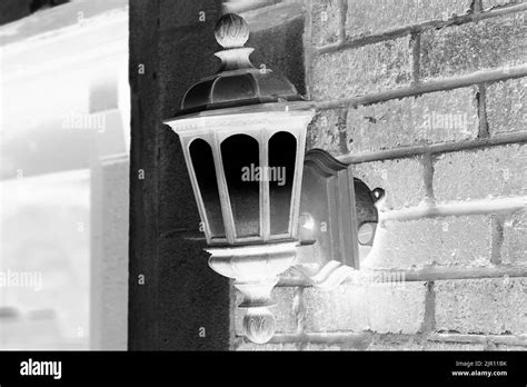 Vintage iron lantern hanging on a brick wall in black and white monochrome film negative Stock ...
