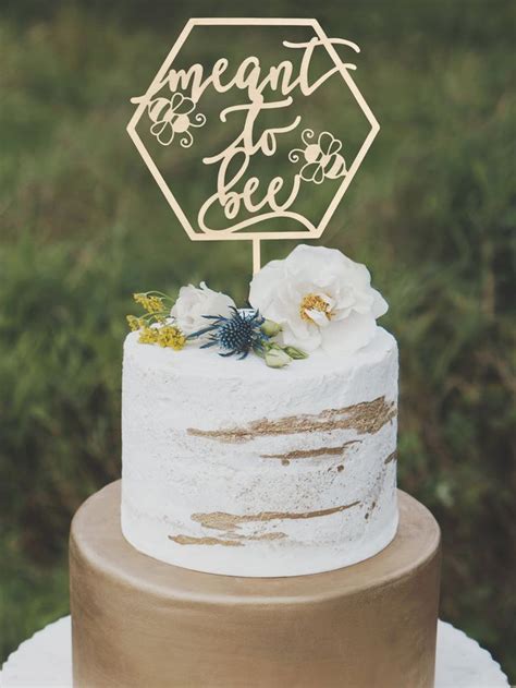 a white cake topped with a wooden sign that says, i am meant to be bee