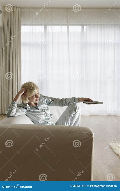 Woman on Couch Watching TV stock image. Image of blond - 33831411