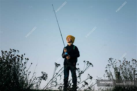 Young boy happily fishing at sunset alone — vacation, horizontal ...