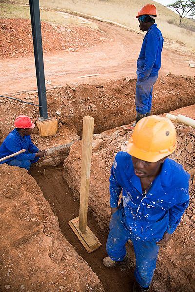 two men in blue work on an excavation