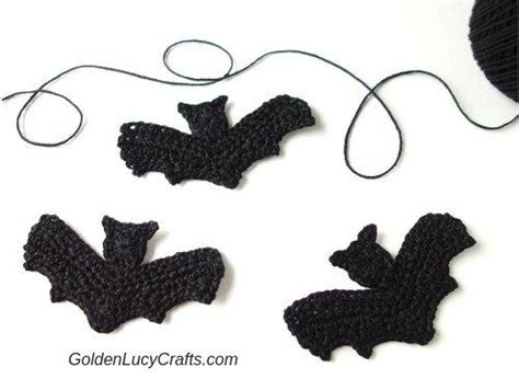 three crocheted bats sitting next to each other on a white surface with yarn