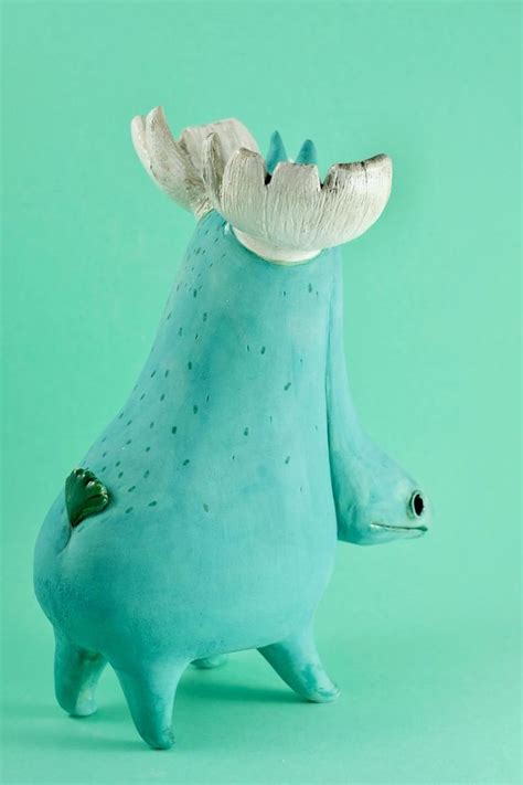 a blue ceramic animal with horns on it's head and eyes, sitting in front of a green background
