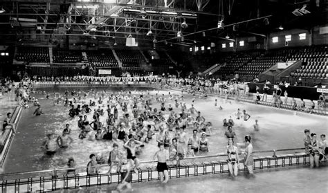 an indoor swimming pool with many people in the water and onlookers ...