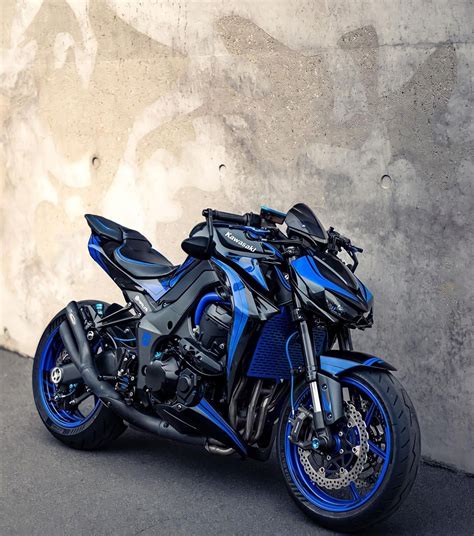 a blue and black motorcycle parked next to a wall