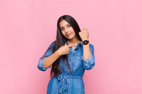 Premium Photo | Young woman looking impatient and angry, pointing at watch