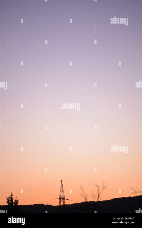 Silhouette shot of a power line tower on top of a hill under a ...