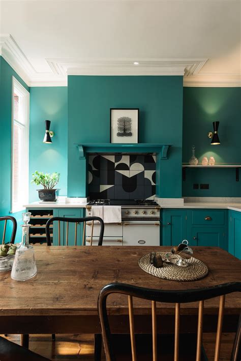 a kitchen with teal walls and wooden table in the foreground is an oven