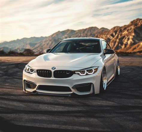 a white car parked on top of a parking lot next to some mountains in ...