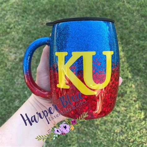 a hand holding a blue and red coffee mug with the letter ku on it