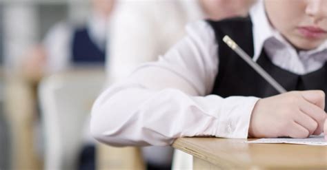 A Child Using A Pencil Writing On A Paper Inside A Classroom · Free ...