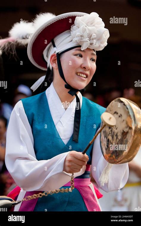 Korean performer in traditional dress bangs a drum in the street during ...