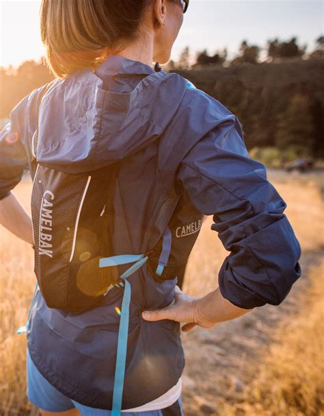 a woman wearing a backpack while standing in a field with her back to the camera