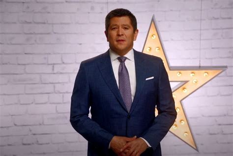 a man in a suit and tie standing next to a wall with a star on it