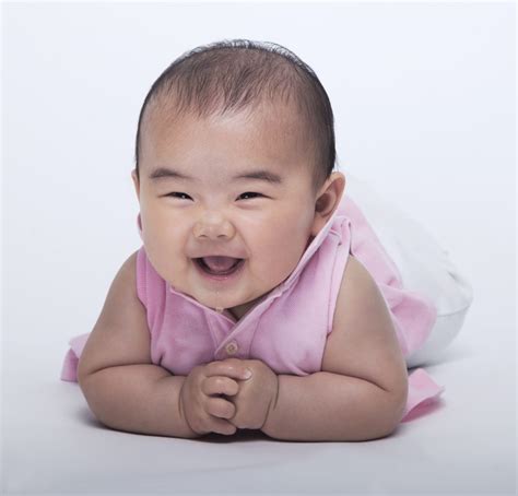 Portrait of smiling and laughing baby lying down, studio shot, white ...