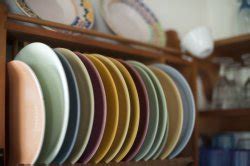 Colorful ceramic plates in a wooden plate rack - Free Stock Image