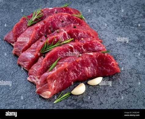 Raw meat, beef steak with seasoning on a black stone table, side view ...
