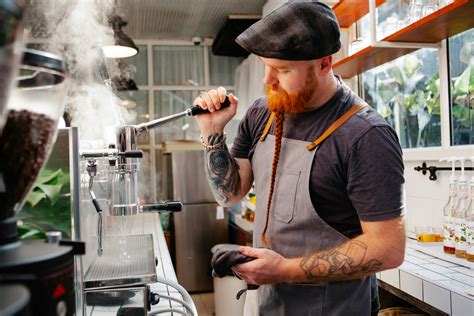 Tattooed barista cleaning coffee maker with steam · Free Stock Photo