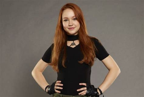 a woman with long red hair and black shirt posing for a photo in front ...