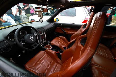 the interior of a car with brown leather seats and people in the background looking at it