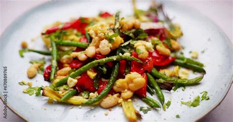 Plate of roasted beans rotating. Vegetarian cooking in 4K. White beans and greens beans. Roasted ...