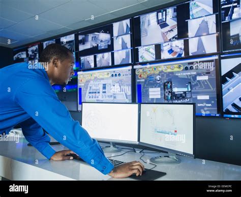 Black security officer watching surveillance cameras Stock Photo - Alamy