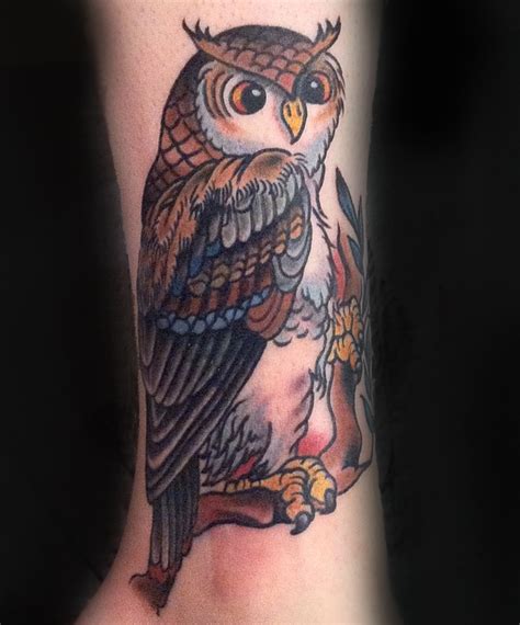 an owl tattoo on the leg of a person's arm with flowers around it